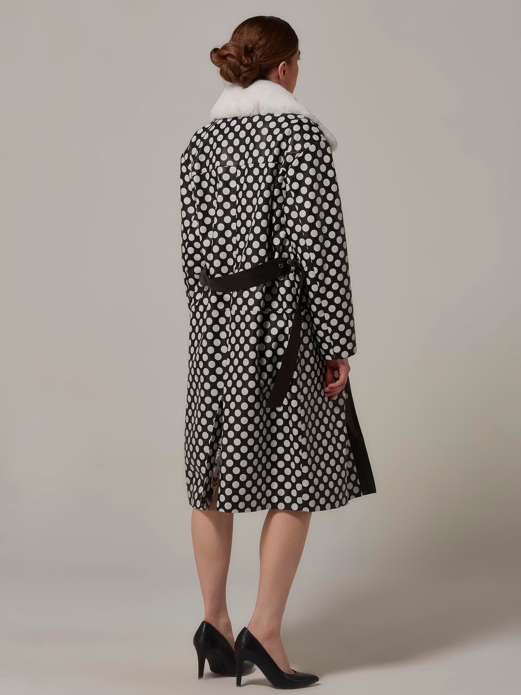 Back view of a stylish woman in a Black and White Leather Coat with Polka Dot and Rex Fur Collar. Full length.