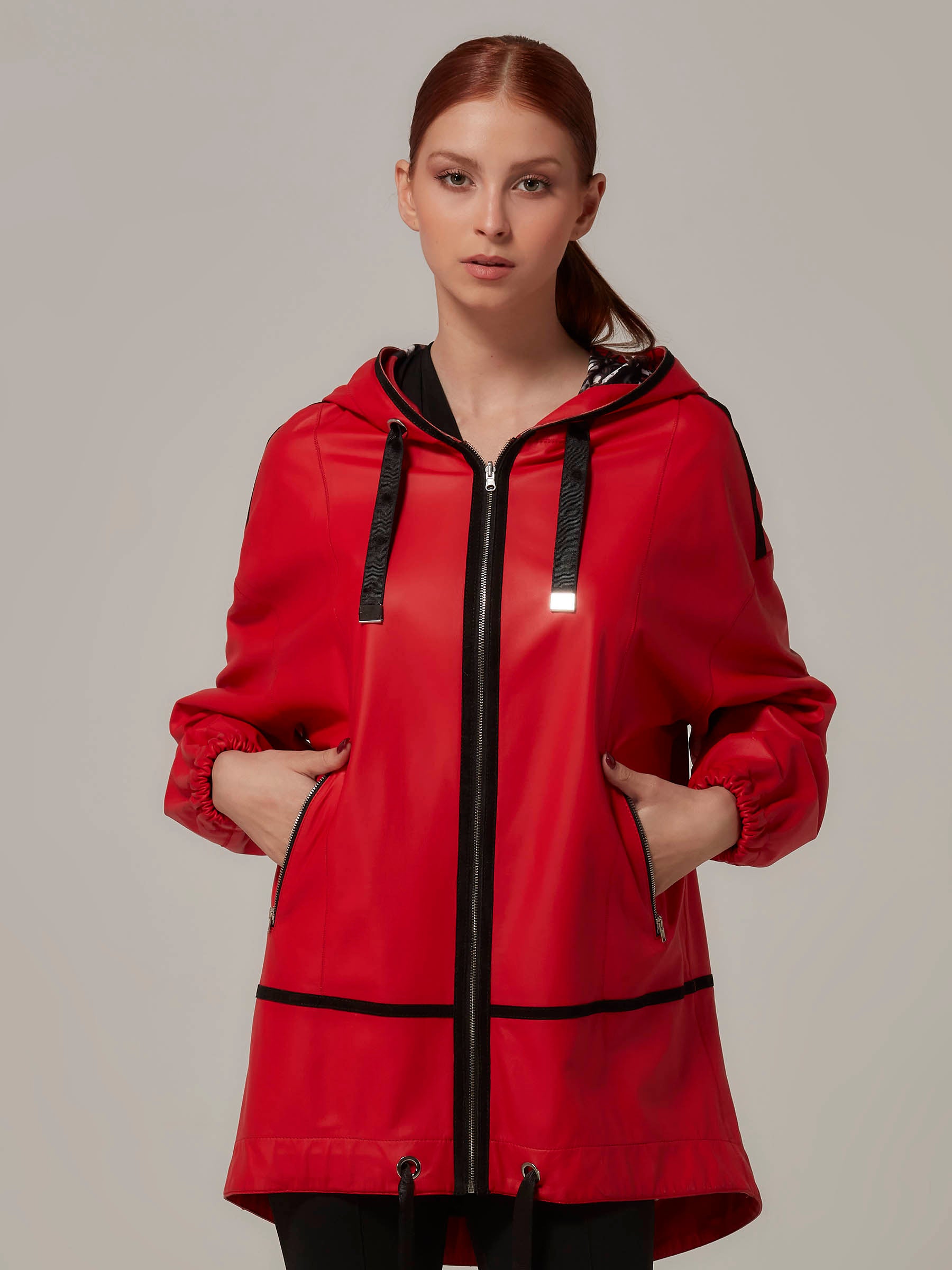 A model wearing a red double-sided leather jacket with a hood, showing the matte red side of the jacket.
